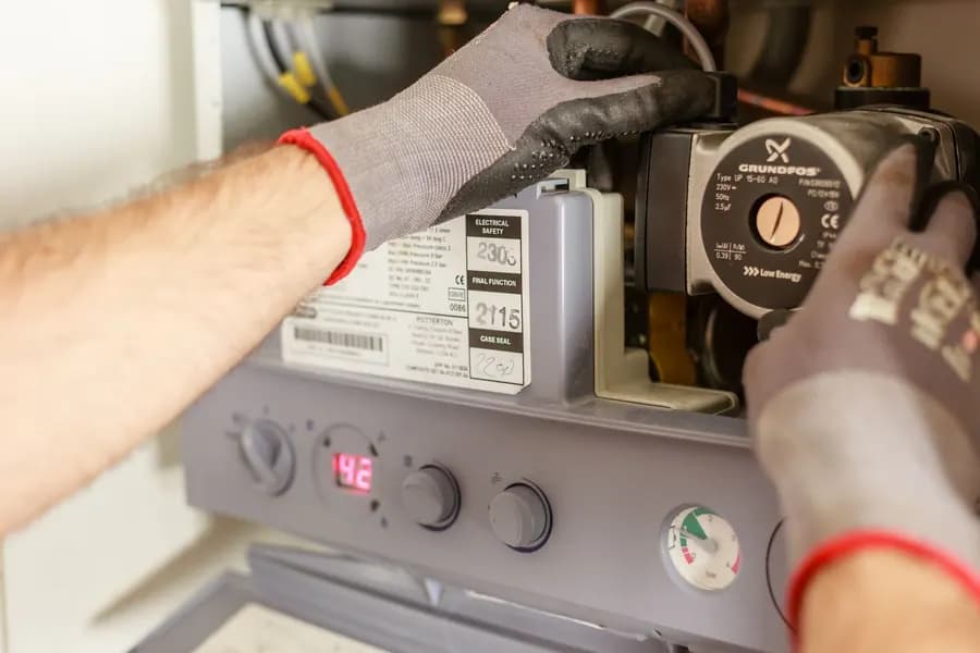 Hands adjusting a boiler control panel