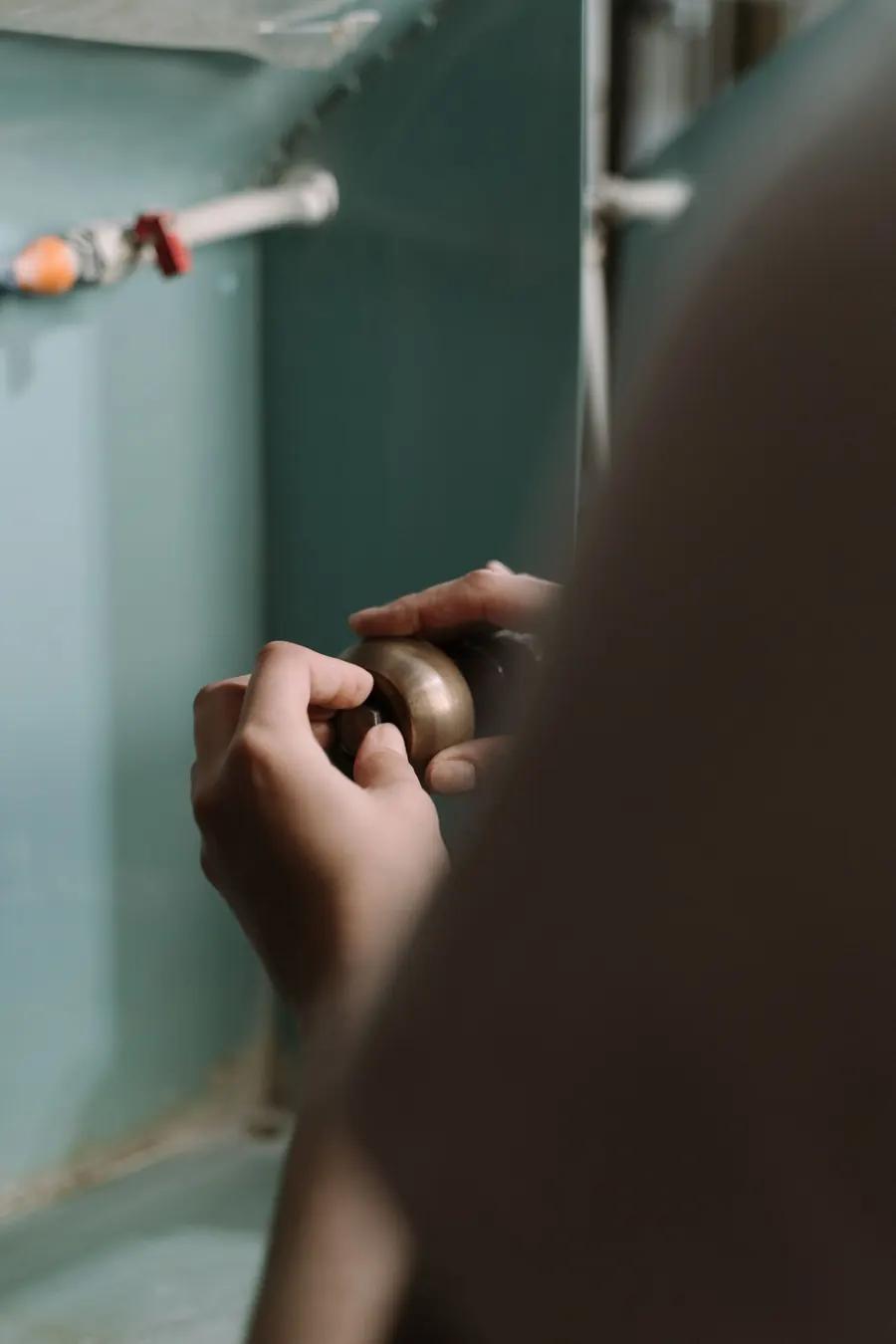 Hands repairing pipework beneath a kitchen sink