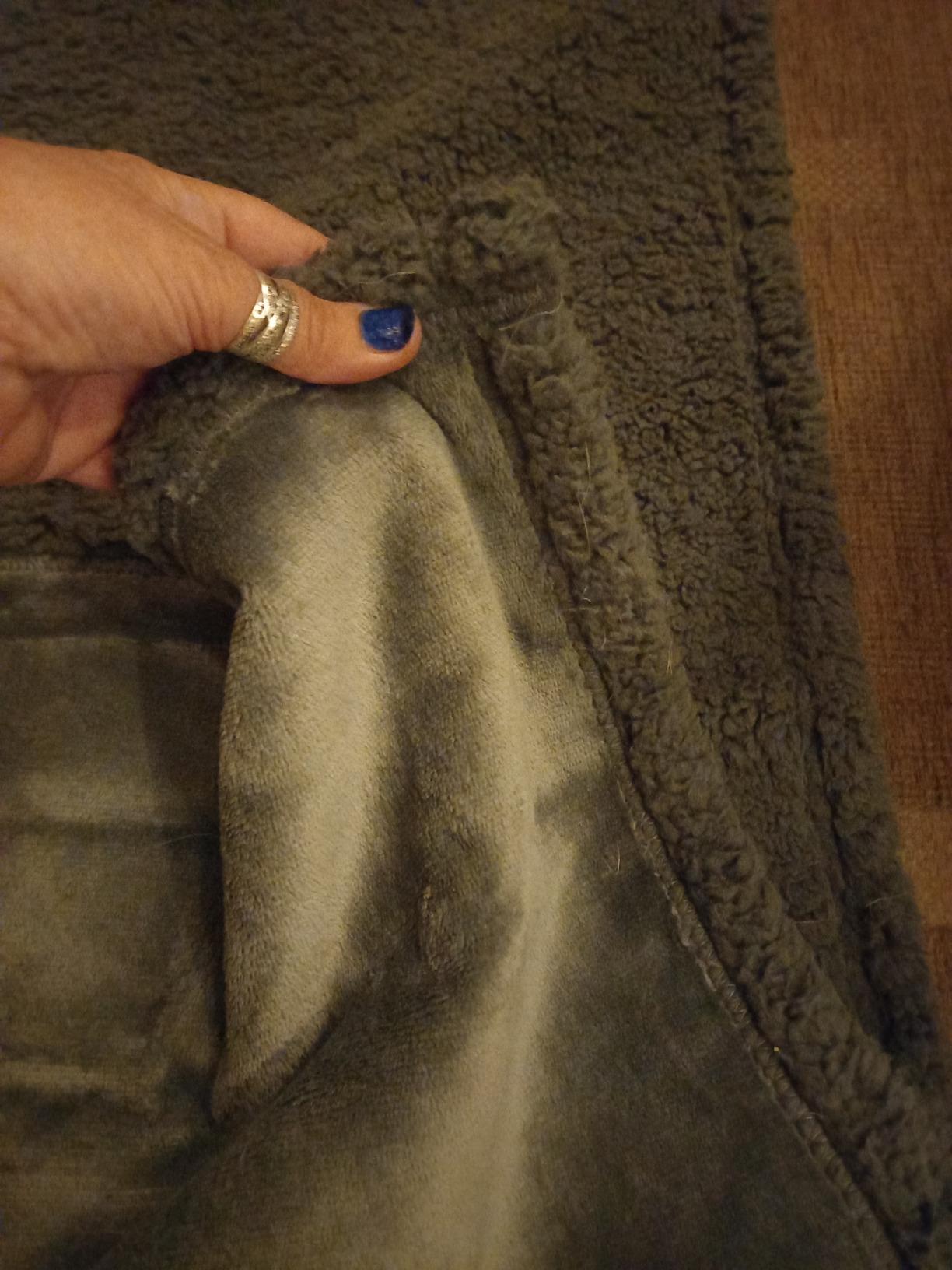 Hand lifting the blanket to show sherpa and velvet faces
